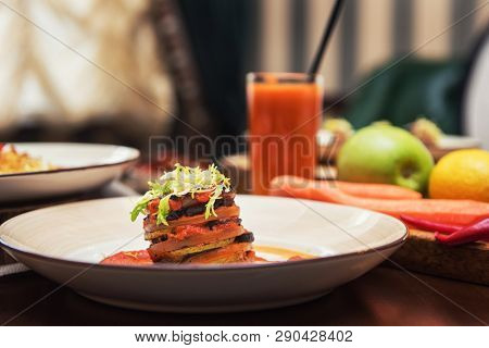 Healthy vegeterian food on brown wood board. Spring vitamin dieting food. Baked vegetables in layers, fruits and carrot juice