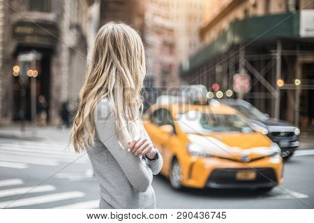 Blonde Woman Standing On City Street And Waiting For Taxi Car At Sunny Day
