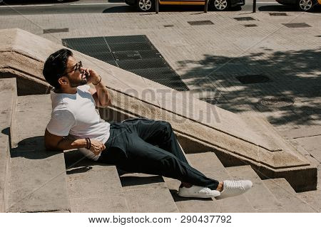 Handsome Bearded Hispanic Man Using Mobile Smartphone For Surfing Web Internet, Making Call And Look
