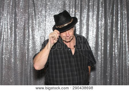 Man in a Photo Booth. A man smiles and poses in a Photo Booth with silver sequin curtains. Photo Booths are fun for all guest. 