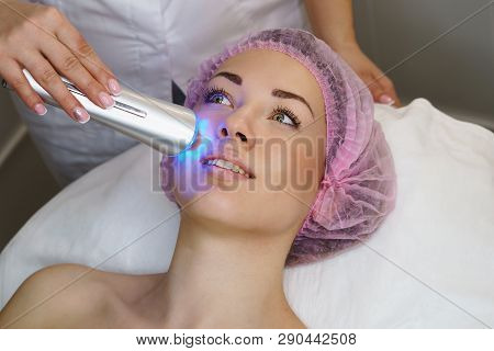 Hardware Cosmetology. Ultrasound Chromotherapy. Beautician Carries Out Procedure For Tightening Skin