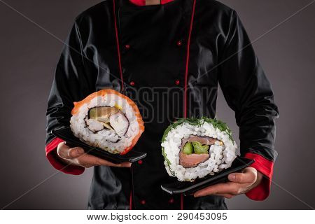 Closeup of master chef holding plates with giant sushi pieces. Concept of asian food