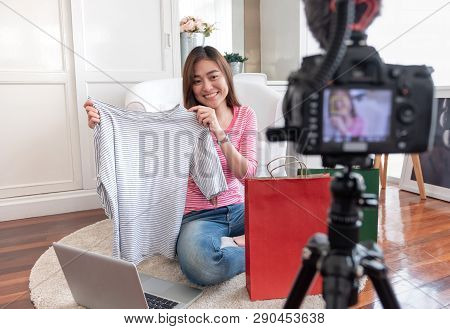 Asian Young Female Blogger Recording Vlog Video With Review Cloths T-shirt At Home Online Influencer