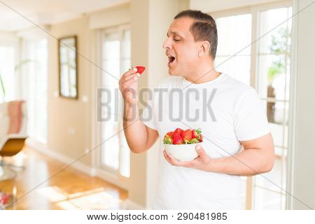 Middle age man eating straweberry at home