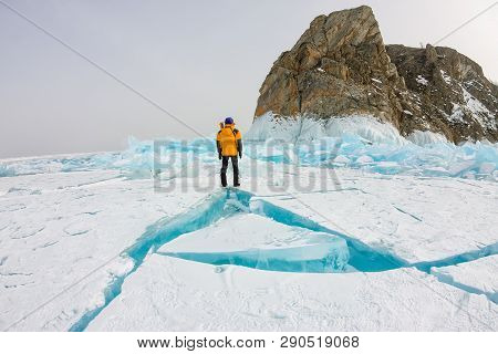 Man Stands Near Cape Khoboy Rock On Olkhon Island, Lake Baikal, Ice Hummocks In Winter, Russia, Sibe