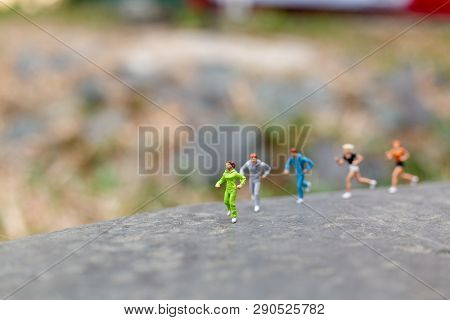 Miniature People Running On The Rock , Health And Lifestyle Concepts.