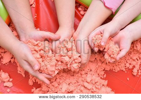 Children Play With Pink Kinetic Sand For Sculpting Figures. Top View, Hands Close Up