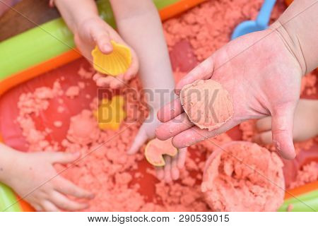 Children Play With Pink Kinetic Sand For Sculpting Figures. Top View, Hands Close Up