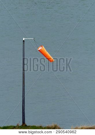 Orange Wind Sock Hanging Limply In Light Wind By Sussex Harbour.