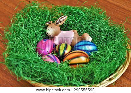 Decorative Clay Hare Lying In The Grass With Painted Eggs