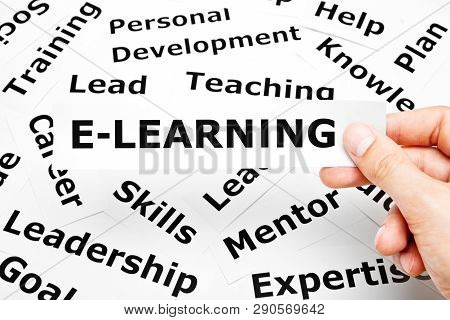 Hand Holding A Piece Of Paper With The Word E-learning Printed On It Above Other Related Words On Th