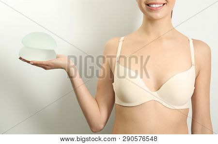 Woman Holding Silicone Implants For Breast Augmentation On White Background, Closeup. Cosmetic Surge