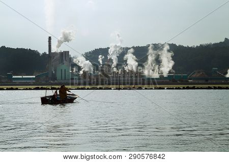 Paper Mill Factory Near A Sea Loch On Pontevedra, Spain And A Fisherman Boat. Pollution Concept