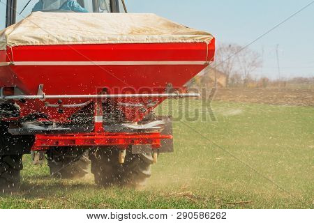 Unrecognizable Farmer In Agricultural Tractor Is Fertilizing Wheat Crop Field With Npk Fertilizer Nu
