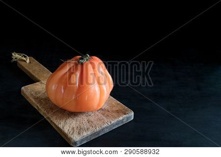 Colorful Juicy Ugly Tomato On Wooden Cutting Board On A Black Backgound, Rustic Style And Low Key