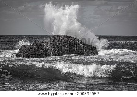 Black And White Seascape, Sea Wave Breaks On A Black Stone, White Spray, The Power Of The Ocean