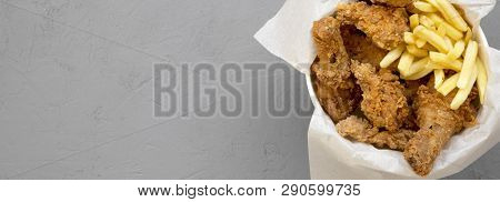 Tasty Fastfood: Fried Chicken Legs, Spicy Wings, French Fries And Chicken Strips In Paper Box Over G