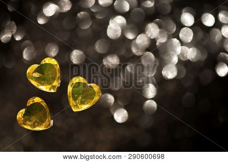 Shiny Yellow, Heart Shape Glass, Jewelry, Placers On A Black Background With Blurred Spots.