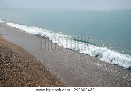 Beautiful Seaside Landscape With Calm Sea Surf Waves Runs To The Empty Sandy Beach And Sun Reflecton