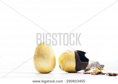 Stylish Easter Egg In Golden Foil And Broken Chocolate Egg With Chocolate Pieces In White Light With