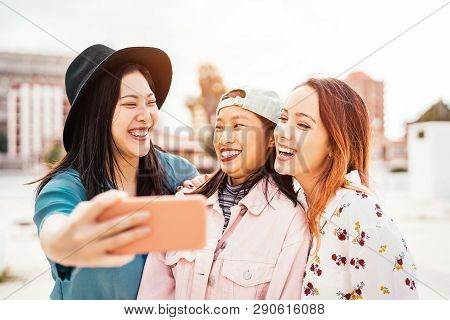 Happy Asian Girls Taking Selfie With Mobile Smartphone Outdoor - Young Trendy Teenager Having Fun Wi