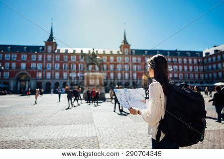 Visiting Famous Landmarks And Places.cheerful Female Traveler At Famous Plaza Mayor Square Reading A