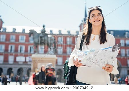 Visiting Famous Landmarks And Places.cheerful Female Traveler At Famous Plaza Mayor Square Reading A