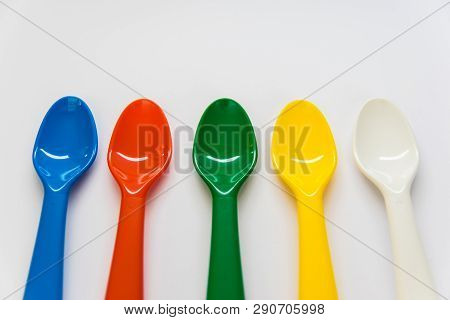 Multicolor Plastic Spoons On The White Background. White, Yellow, Green, Red, Blue Spoons Can Be Use
