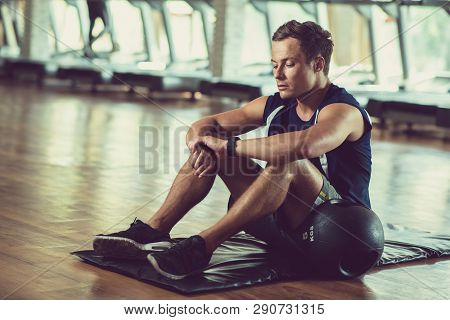 Spotsman Checking Pulse On Hid Smart Watch After Training With Medicine Ball In Gym