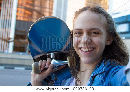 Portrtait Photo Of Smiling Teen Girl Holding A Skateboard On Her Shoulder