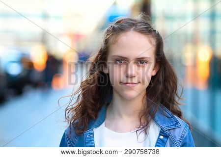 Young Girl Smiles And Looks At The Camera.background City In Blur