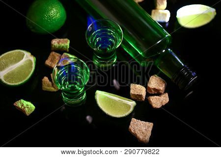 Absinthe Poured Into A Glass. Absinthe Shots With Sugar Cubes. Bottle Of Absinthe And Glasses With B