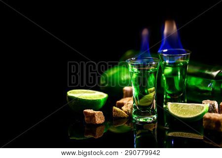 Concept Of Elite Alcohol. Absinthe Poured Into A Glass. Burning Sugar. In The Background Is A Bottle