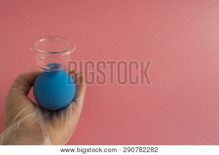 Female Hand With French Manicure In Medicine Glove Holds Blue Cosmetic Medical Jar For Vacuum Facial