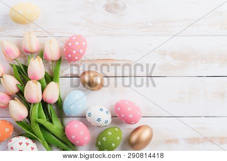 Happy Easter! Colourful Of Easter Eggs In Nest With Pink Tulip Flower And Feather On Wooden Backgrou