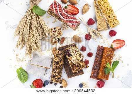 Assortment Of Different Granola Cereal Bars On White Stone Background. Healthy Pre Or Post Workout S