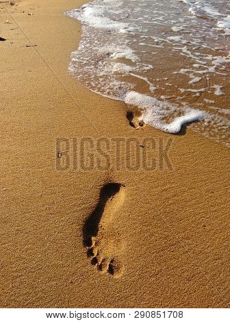 Lonely Footprint At The Beach. Trace At Sand And Sea Wave. Peaceful Lonely Mood. Psychology Or Phylo
