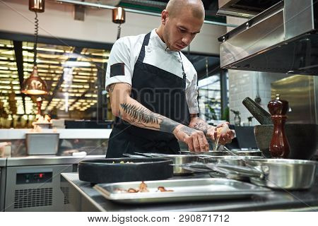 Important Ingredient. Concentrated Young Chef Breaking An Egg For Traditional Italian Pasta While St