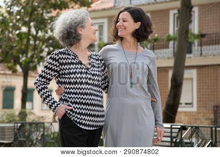 Cheerful Smiling Mother And Daughter Walking Around Uptown Old District. Young And Senior Women Hugg