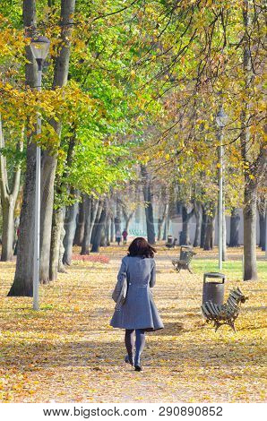 Girl With Black Hair Walks In A Beautiful Park In Autumn, With Autumnal Colored Leaves, Foliage And 