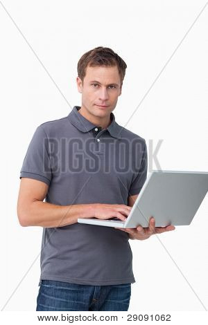 Young man standing hänen laptop valkoista taustaa vasten