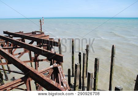 Weathered wooden posts and iron sub structure of the Victorian pier at Hastings in East Sussex, England.