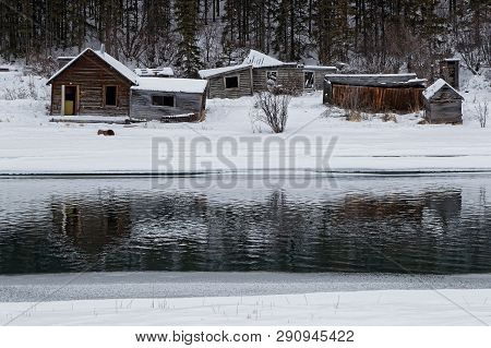 Old Ruined Wooden Houses In Carcross Reflects In The River