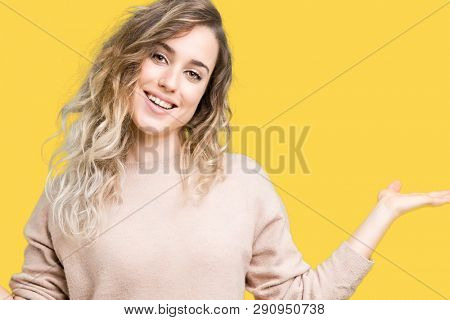 Beautiful young blonde woman wearing sweatershirt over isolated background Smiling showing both hands open palms, presenting and advertising comparison and balance