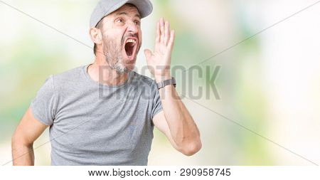 Handsome middle age hoary senior man wearing sport cap over isolated background shouting and screaming loud to side with hand on mouth. Communication concept.