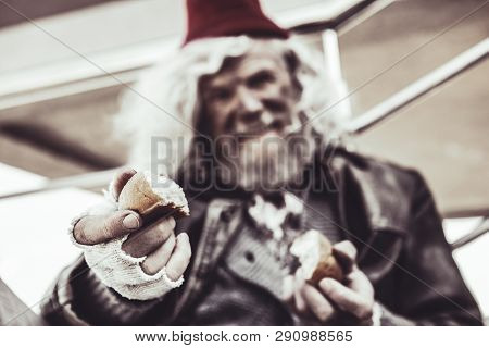 Close Up Of Old Almsman Whose Holding Pieces Of Baking And Sharing It With Photographer.