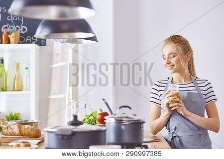The Girl At The Table In The Kitchen With A Glass Of Orange Jui