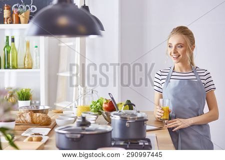 The Girl At The Table In The Kitchen With A Glass Of Orange Jui