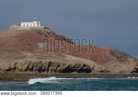 Coastal Landscape And Arinaga Lighthouse In The Background.