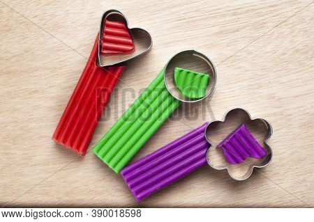 Several Pieces Of Plasticine Lie On A Wooden Board With Molds In The Form Of A Flower, A Heart And A